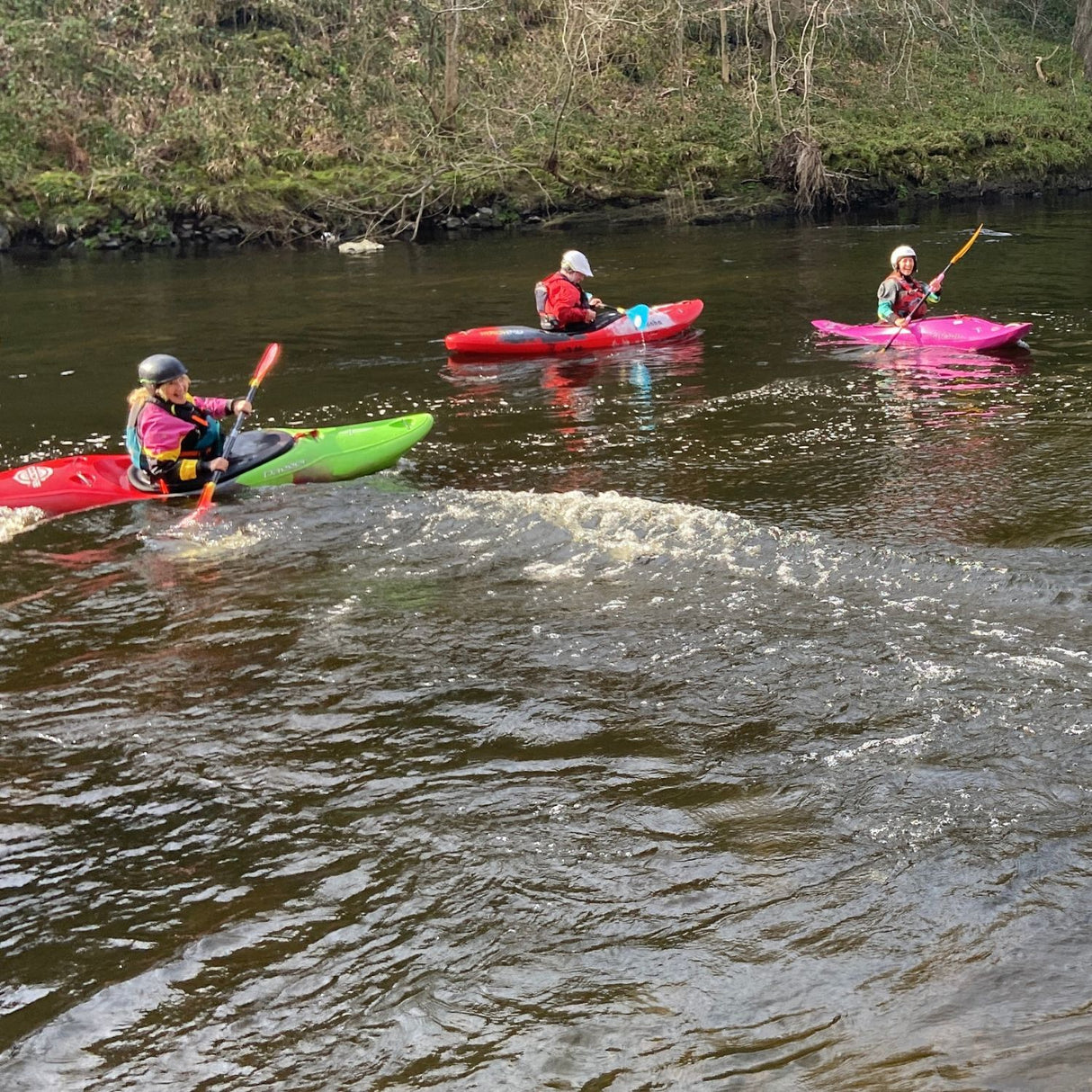 Three kayakers paddling on a river in Dulbin