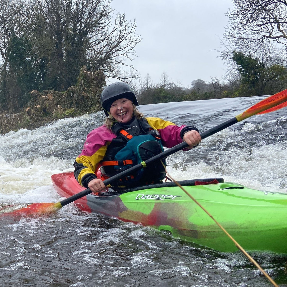 Person kayaking in a green kayak on a river with rapids in Dublin.