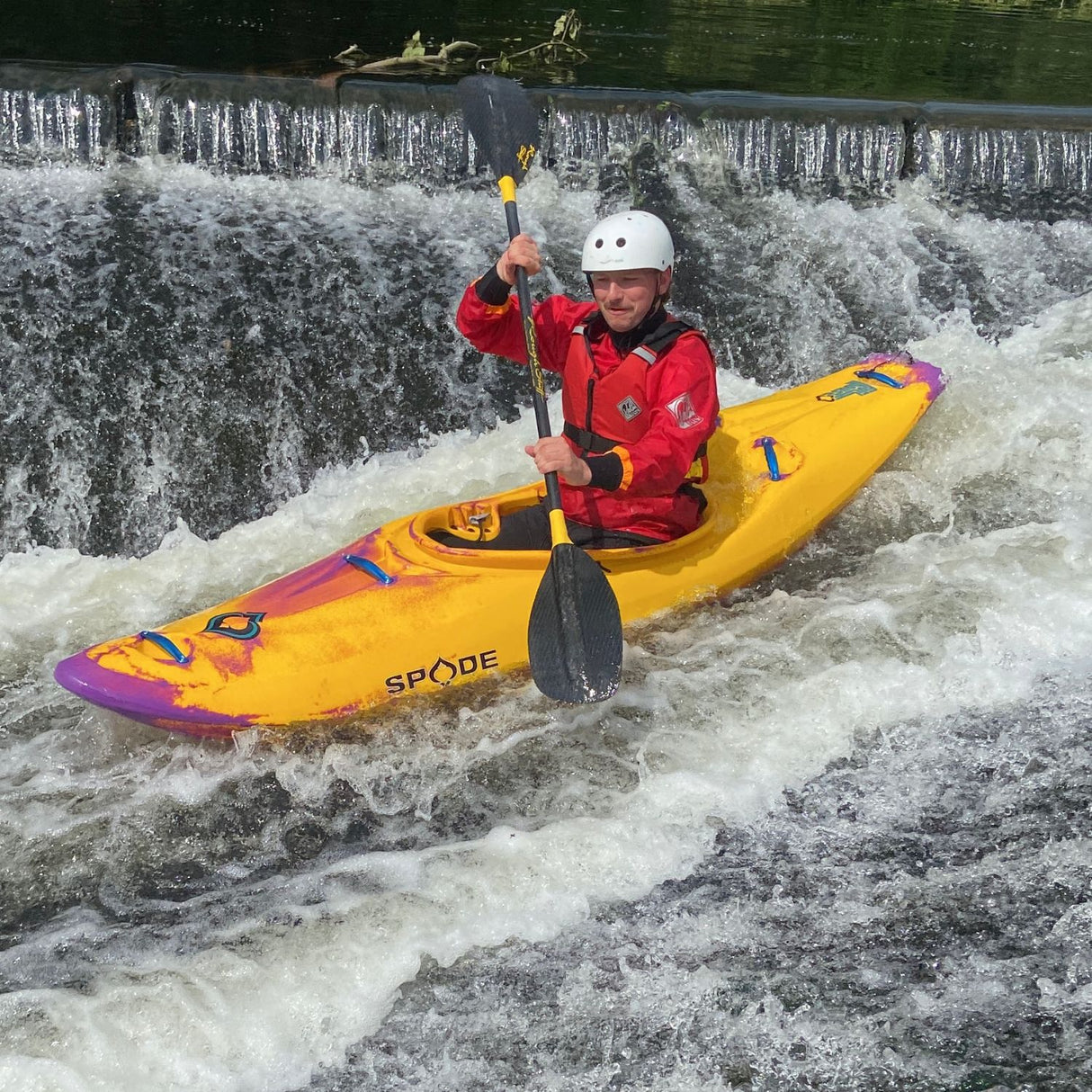 Person kayaking in rapids with a yellow kayak and helmet.