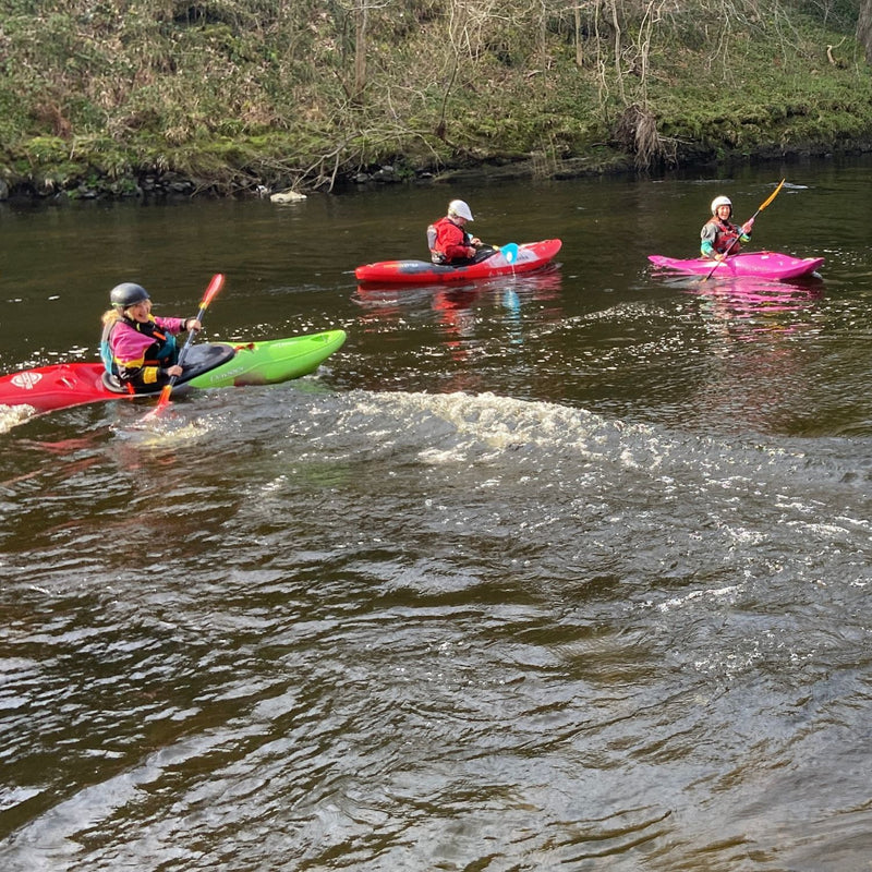 Three kayakers paddling on a river in Dulbin