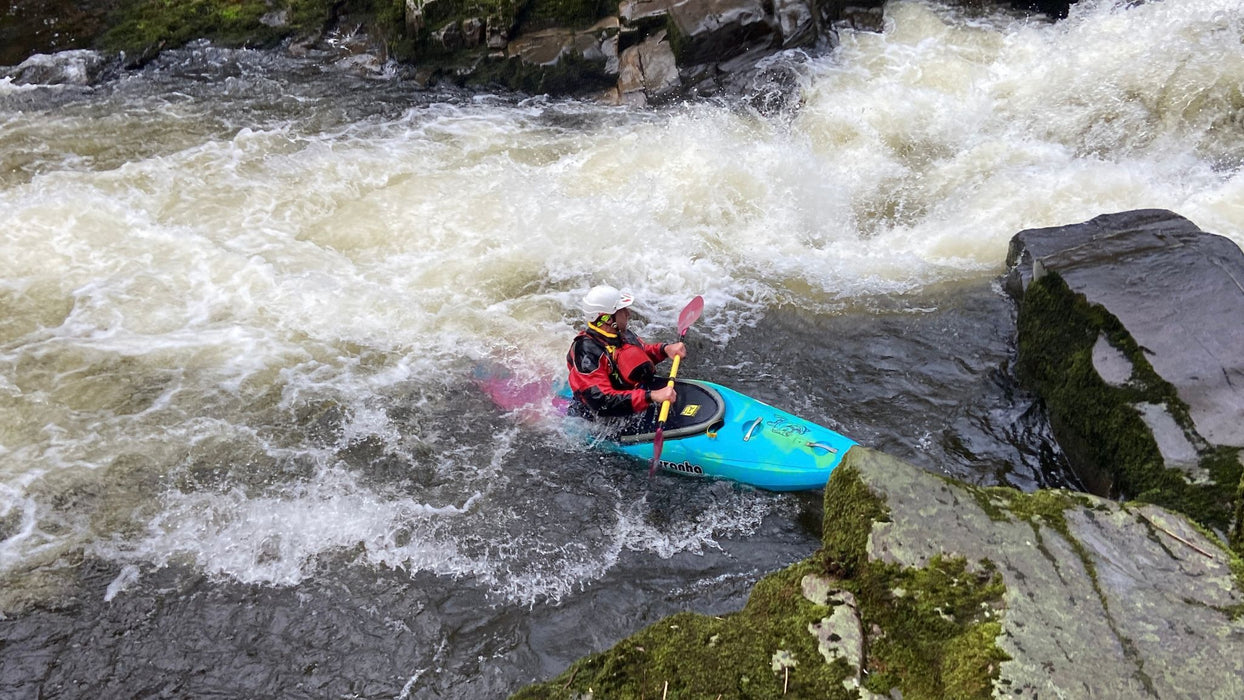 Person kayaking in a river with rapids and rocks